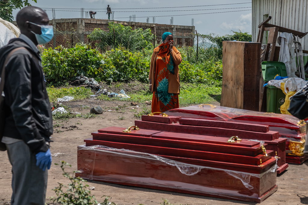 Family members of people who died of Ebola stand next to coffins at a health center in Rwampara, Congo, Wednesday, May 20, 2026. (AP Photo/Moses Sawasawa)