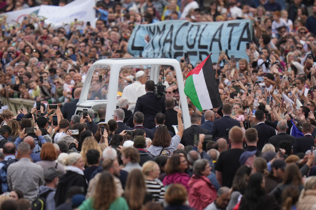 Pope Leo XIV rides on his popemobile next to a Palestinian flag at the end of a Mass for the Jubilee of Migrants and Missionaries in St. Peter's Square at the Vatican, Sunday, Oct. 5, 2025. (AP Photo/Alessandra Tarantino)