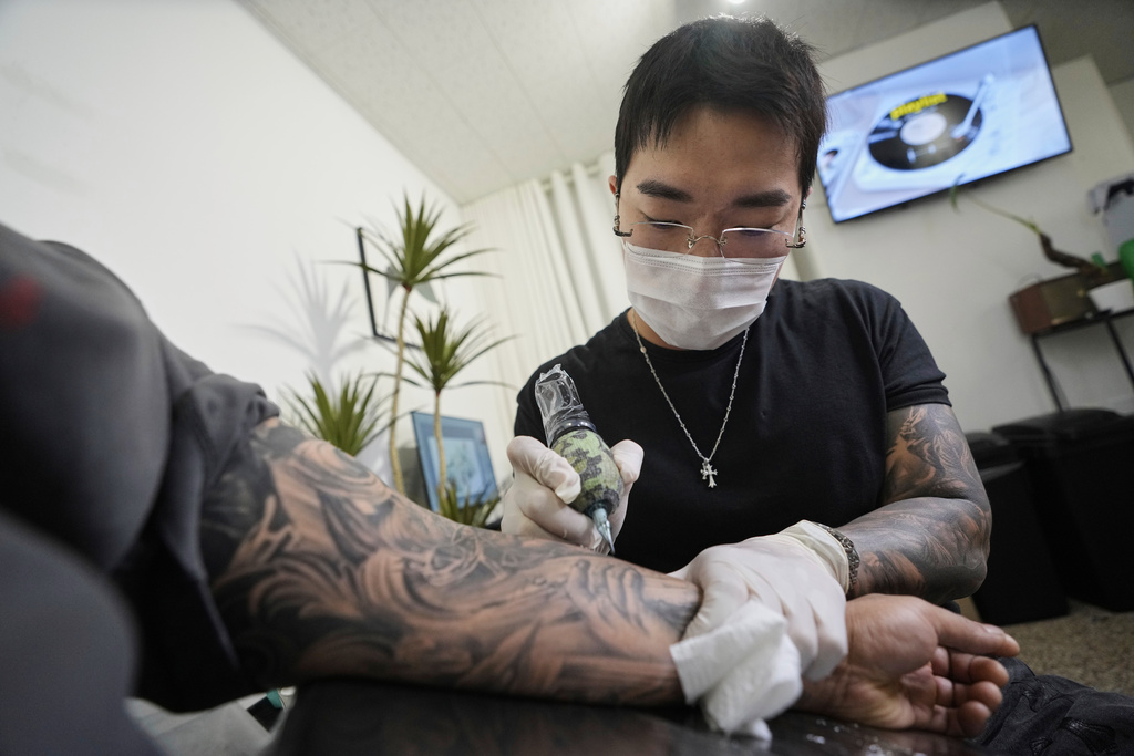 Tattoo artist Song Jaemin works to tattoo an image of Jesus Christ on the forearm of Lee Byong-joo at his studio in Goyang, South Korea, Thursday, Sept. 18, 2025. (AP Photo/Ahn Young-joon)