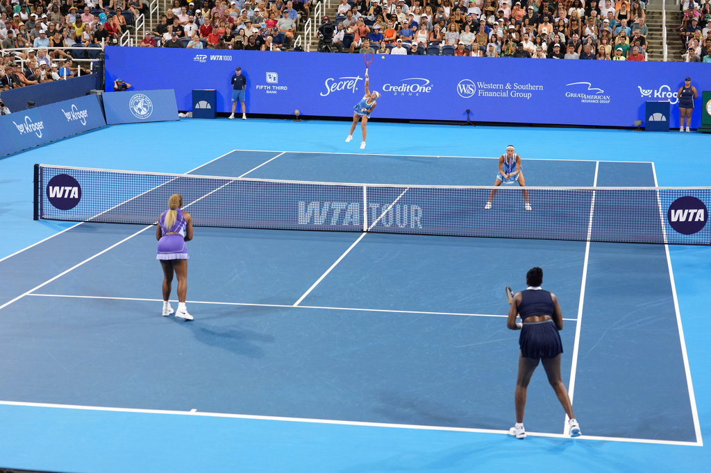 As Peyton Stearns, top right, of the United States, looks on, Marta Kostyuk, top center, of Ukraine, serves against Serena Williams, bottom left, and Venus Williams, bottom right, also of the United States, during a women's doubles match at the Cincinnati Open tennis tournament, Monday, Aug. 17, 2026, in Mason, Ohio. (AP Photo/Kareem Elgazzar)