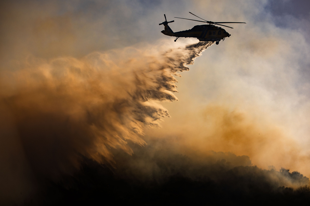 A helicopter drops water on the Sandy Fire, Monday, May 18, 2026, in Simi Valley, Calif. (AP Photo/Ethan Swope)