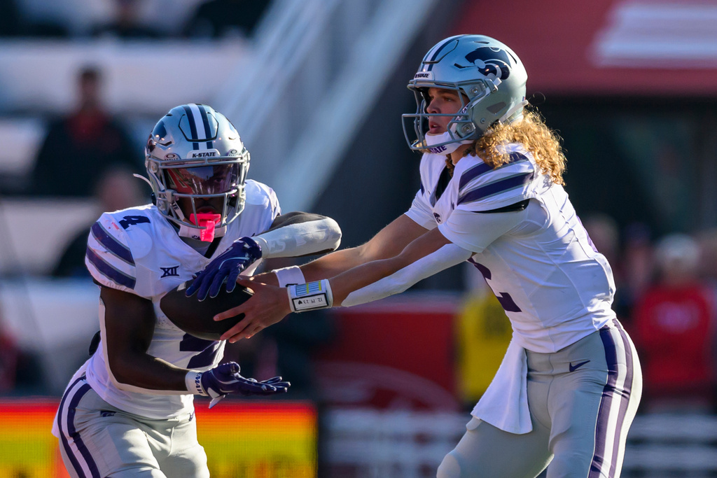 Kansas State quarterback Avery Johnson, right, hands the ball off to running back Joe Jackson, left, during the first half of an NCAA college football game against Utah, Saturday, Nov. 22, 2025, in Salt Lake City. (AP Photo/Tyler Tate)