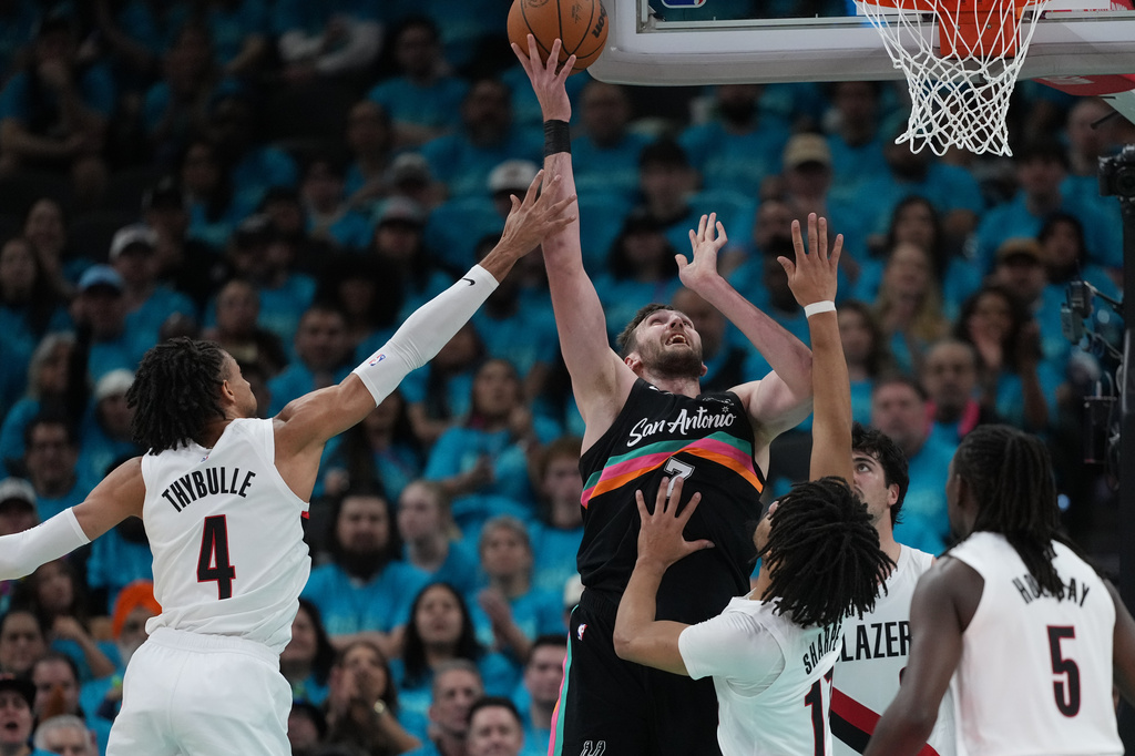 San Antonio Spurs center Luke Kornet (7) scores over Portland Trail Blazers guard Shaedon Sharpe (17) during the first half in Game 1 of a first-round NBA playoffs basketball series in San Antonio, Sunday, April 19, 2026. (AP Photo/Eric Gay)
