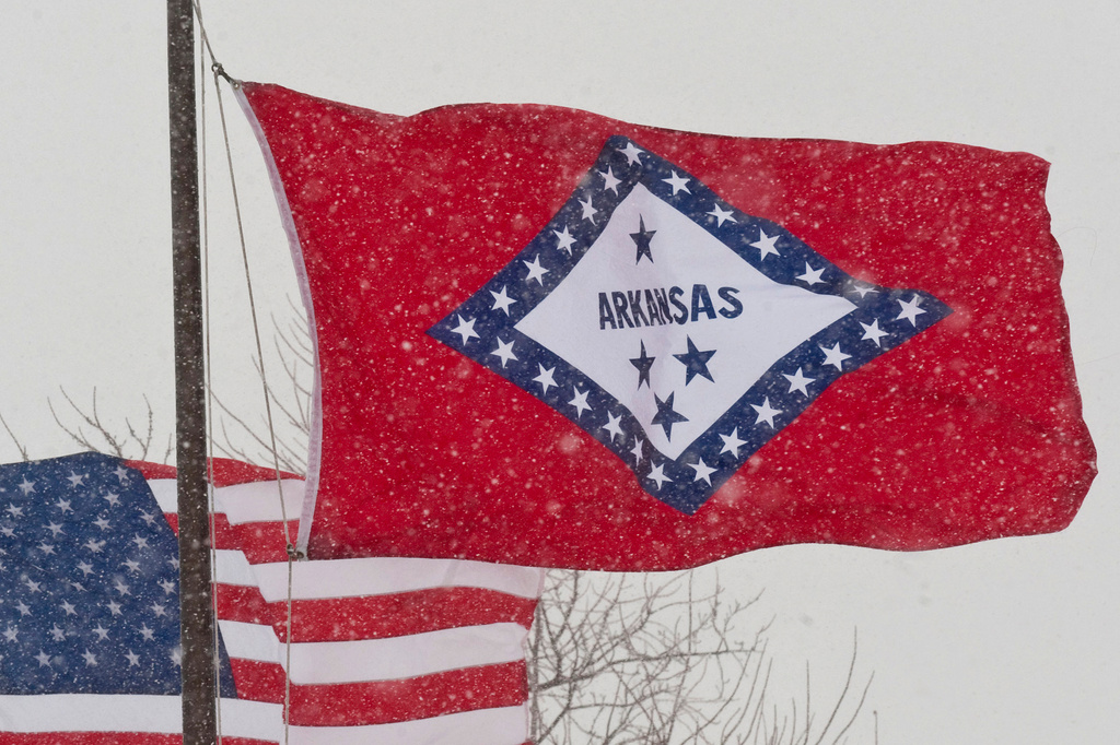 FILE - An Arkansas flag flies in the wind as snow falls in Fayetteville, Ark., Feb. 1, 2011. (AP Photo/Beth Hall, File)