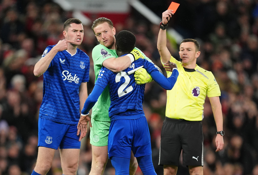 Everton's Idrissa Gueye, second right, is held back by teammate Jordan Pickford as he argues with Michael Keane, left, after getting a red card from referee Tony Harrington during the English Premier League soccer match between Manchester United and Everton in Manchester, England, Monday, Nov. 24, 2025. (Martin Rickett/PA via AP)