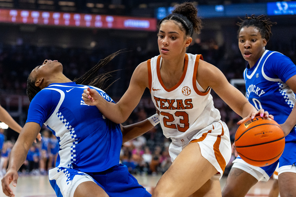 Texas guard Aaliyah Crump (23) drives to the basket between Kentucky guard Tonie Morgan, left, and forward Jordan Obi (0) during the second half of an NCAA college basketball game Monday, Feb. 9, 2026, in Austin, Texas. (AP Photo/Stephen Spillman)