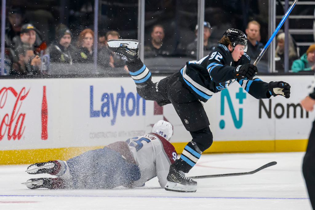 Utah Mammoth center Logan Cooley (92) is tripped by Colorado Avalanche left wing Victor Olofsson (95) during the second period of an NHL hockey game Tuesday, Oct. 21, 2025, in Salt Lake City, Utah. (AP Photo/Tyler Tate)