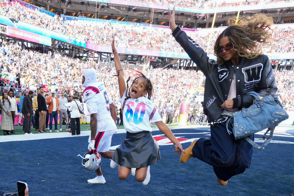 Blue Ivy Carter, right, and Rumi Carter, center, pose for photos in the end zone before the NFL Super Bowl 60 football game between the New England Patriots and the Seattle Seahawks, Sunday, Feb. 8, 2026, in Santa Clara, Calif. (AP Photo/Julio Cortez)