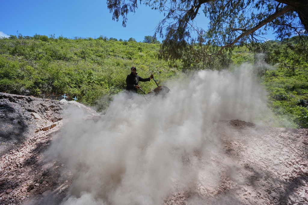 Carlos Martinez discards mercury rocks after baking them in San Joaquin, Mexico, Tuesday, Aug. 19, 2025. (AP Photo/Fernando Llano)