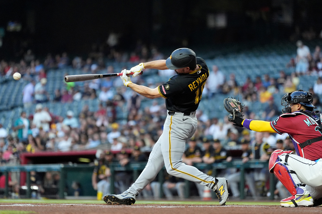 Pittsburgh Pirates' Bryan Reynolds, left, connects for a single as Arizona Diamondbacks catcher Gabriel Moreno reaches for the ball during the first inning of a baseball game, Wednesday, May 6, 2026, in Phoenix. (AP Photo/Ross D. Franklin)