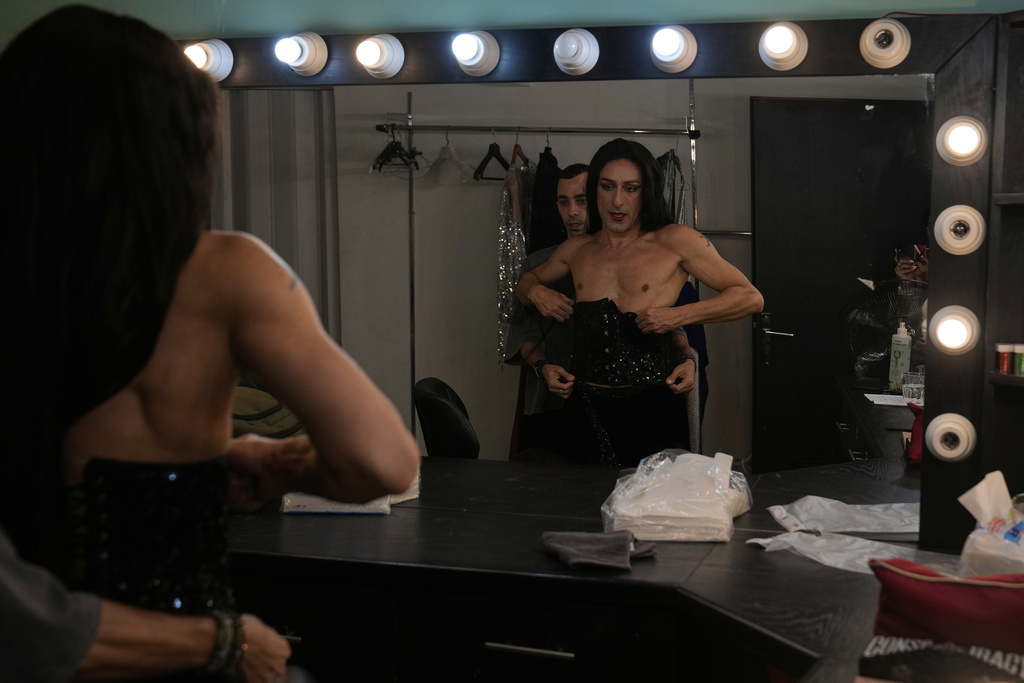 Alexandre Paulikevitch is helped into his dress by an assistant backstage before performing at a theatre in Beirut, Lebanon, Thursday, Sept. 11, 2025. (AP Photo/Hussein Malla)