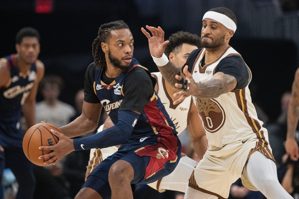 Cleveland Cavaliers' Darius Garland, left, keeps the ball from Golden State Warriors' Gary Payton II, right, during the first half of an NBA basketball game in Cleveland, Saturday, Dec. 6, 2025. (AP Photo/Phil Long)