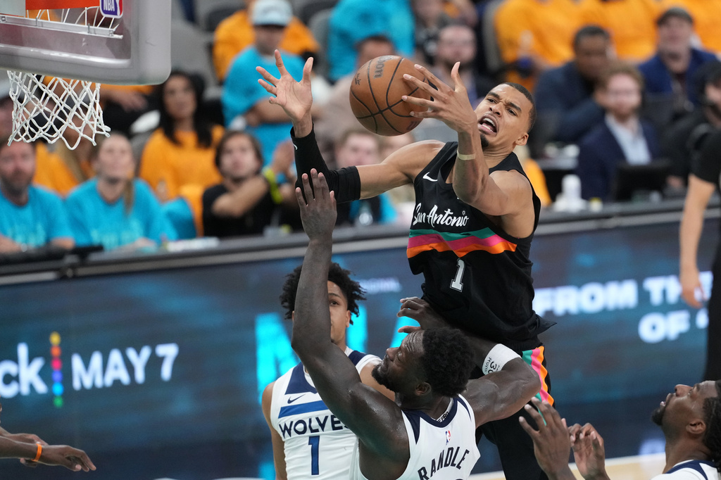 San Antonio Spurs forward Victor Wembanyama (1) reaches for the ball as Minnesota Timberwolves forward Julius Randle (30) defends during the second half in Game 1 of a second-round NBA playoffs basketball series in San Antonio, Monday, May 4, 2026. (AP Photo/Eric Gay)