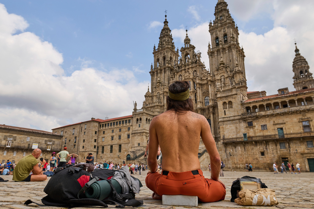 Pilgrims and tourists rest in front of the cathedral in Santiago de Compostela, northwestern Spain, Thursday, Aug. 21, 2025. (AP Photo/Lalo Villar)
