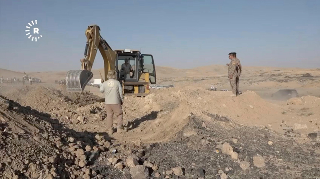 In this image taken from video provided by Rudaw TV, workers dig out human remains at the Khasfa site near the northern Iraqi city of Mosul, where authorities have begun excavating a mass grave believed to contain thousands of victims of the Islamic State (IS) Mosul, Iraq, Sunday, Aug. 17, 2025. (Rudaw TV via AP)