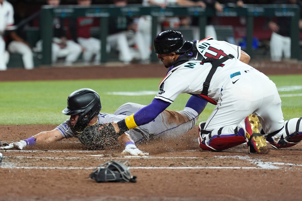 Arizona Diamondbacks catcher Gabriel Moreno, right, tags out Colorado Rockies' Ezequiel Tovar at home plate during the fifth inning of a baseball game, Thursday, May 21, 2026, in Phoenix. (AP Photo/Ross D. Franklin)