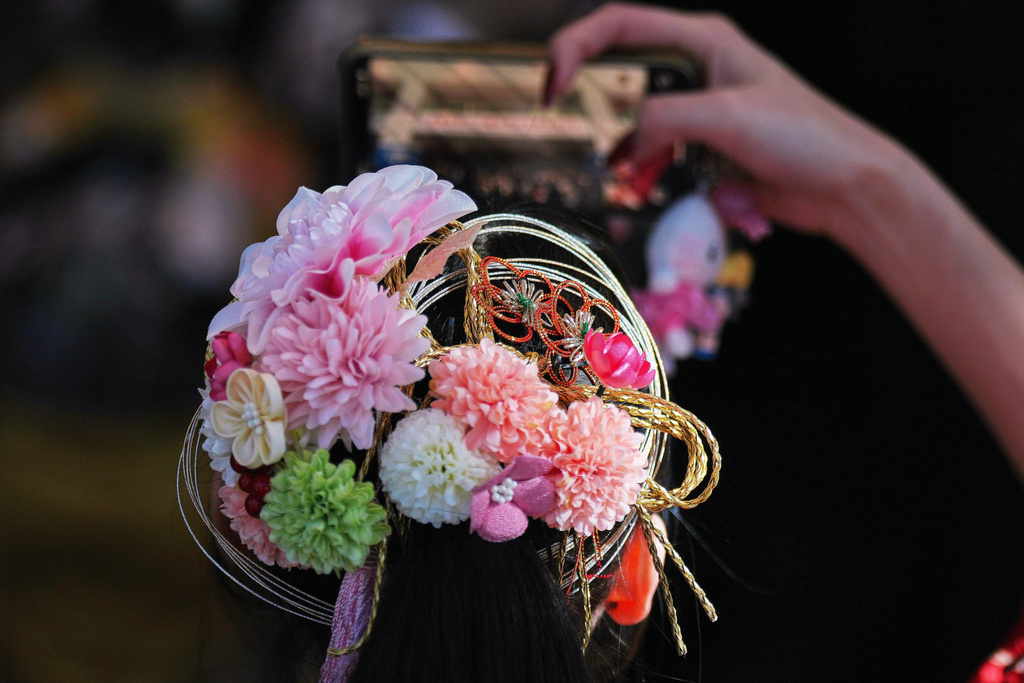 A young adult with hair ornament takes a photo, during a ceremony of the Coming-of-Age Day, a centuries-old tradition and national holiday marking the milestone from childhood to adulthood, Monday, Jan. 12, 2026, in Yokohama near Tokyo. (AP Photo/Eugene Hoshiko)