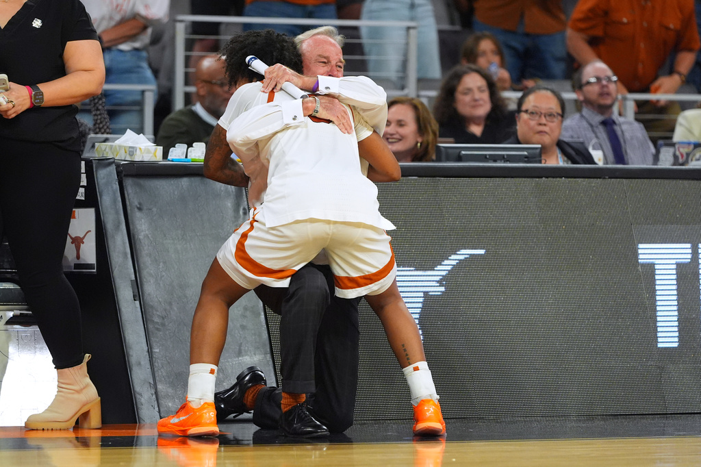 Texas guard Rori Harmon (3) hugs head coach Vic Schaefer against Michigan during the second half in the Elite Eight of the NCAA college basketball tournament, Monday, March 30, 2026, in Fort Worth, Texas. (AP Photo/LM Otero)