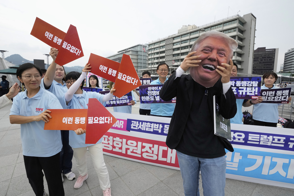 A South Korean protester wearing a mask of U.S. President Donald Trump attends a rally to oppose the planned joint military exercises called Ulchi Freedom Shield, or UFS, between the U.S. and South Korea, near the U.S. Embassy in Seoul, South Korea, Monday, Aug. 11, 2025. The signs at bottom read, "There is no need for such an alliance." (AP Photo/Ahn Young-joon)