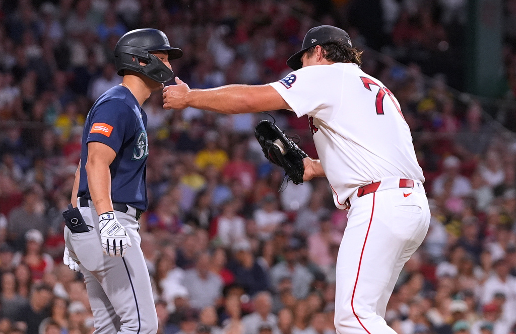 Boston Red Sox's Payton Tolle, right, hugs Seattle Mariners' Dominic Canzone , left, while making a force out on a ground ball during the third inning of a baseball game, Monday, Aug. 31, 2026, in Boston. (AP Photo/Charles Krupa)