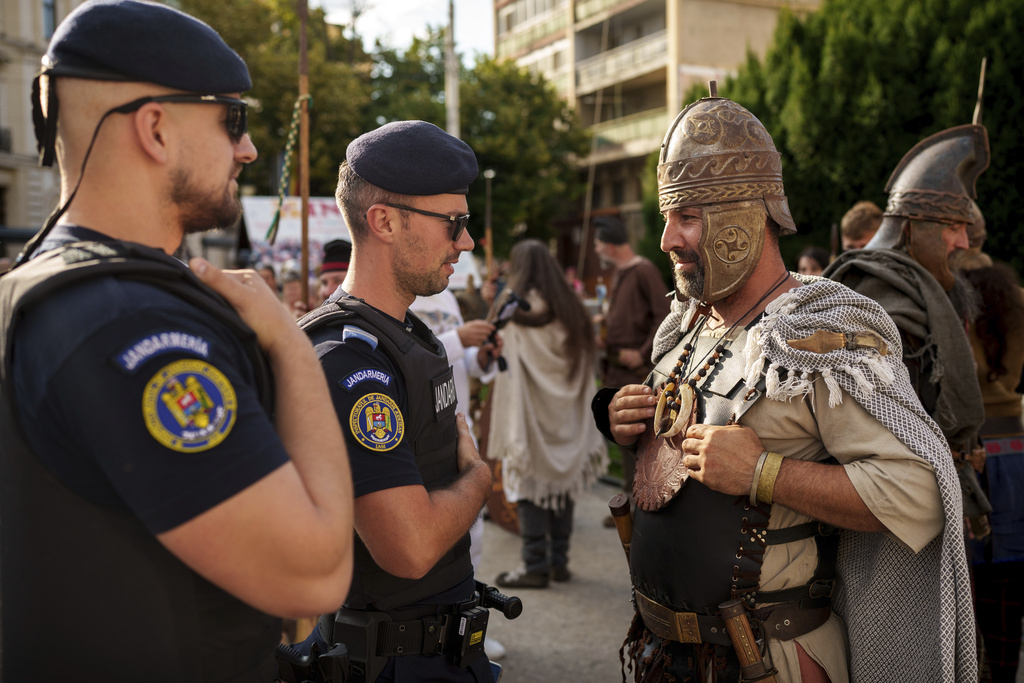 A man wearing a Dacian warrior outfits speaks to Romanian gendarmes in Iasi, Romania, Friday, July 11, 2025 ahead of the Getodava historical reenactment festival. (AP Photo/Vadim Ghirda)