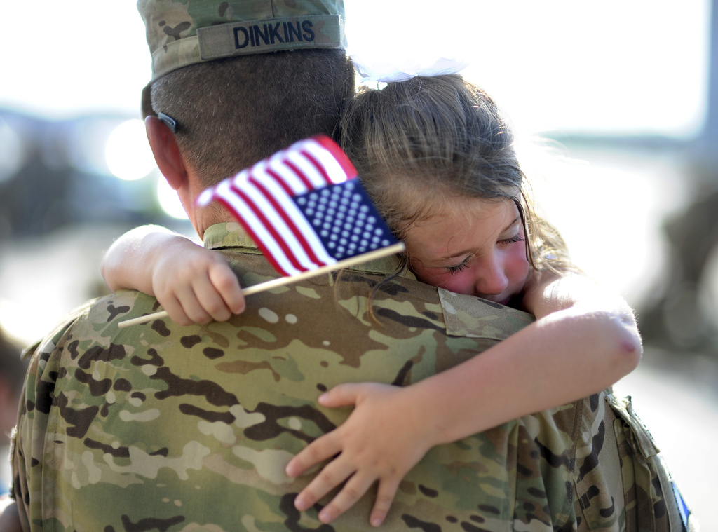 FILE - U.S. Army Staff Sgt. Jason Dinkins with the 3rd Combat Aviation Brigade is hugged by his daughter Olivia Chastain after a welcome home ceremony, Tuesday, June 11, 2013 at Hunter Army Airfield in Savannah, Ga. (AP Photo/Stephen Morton, file)