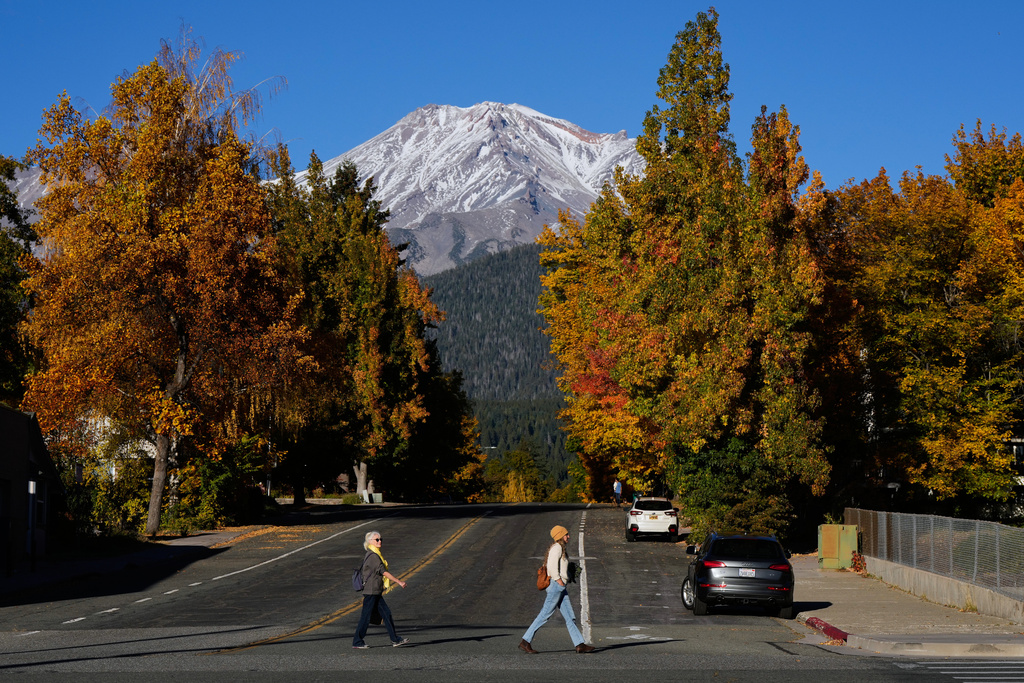 Pedestrians walk across East Lake Street as Mount Shasta is seen in the background, Monday, Oct. 20, 2025, in Mount Shasta, Calif. (AP Photo/Godofredo A. Vásquez)