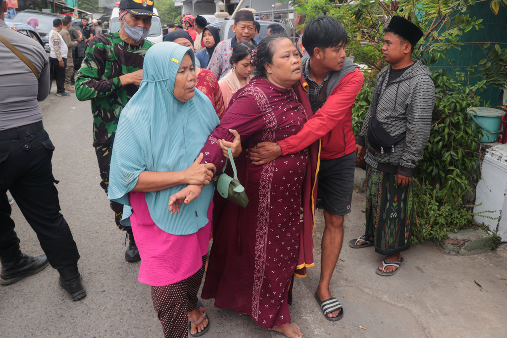 A woman is assisted to walk away after a building collapsed at an Islamic boarding school in Sidoarjo, East Java, Indonesia, Tuesday, Sept. 30, 2025. (AP Photo/Trisnadi)
