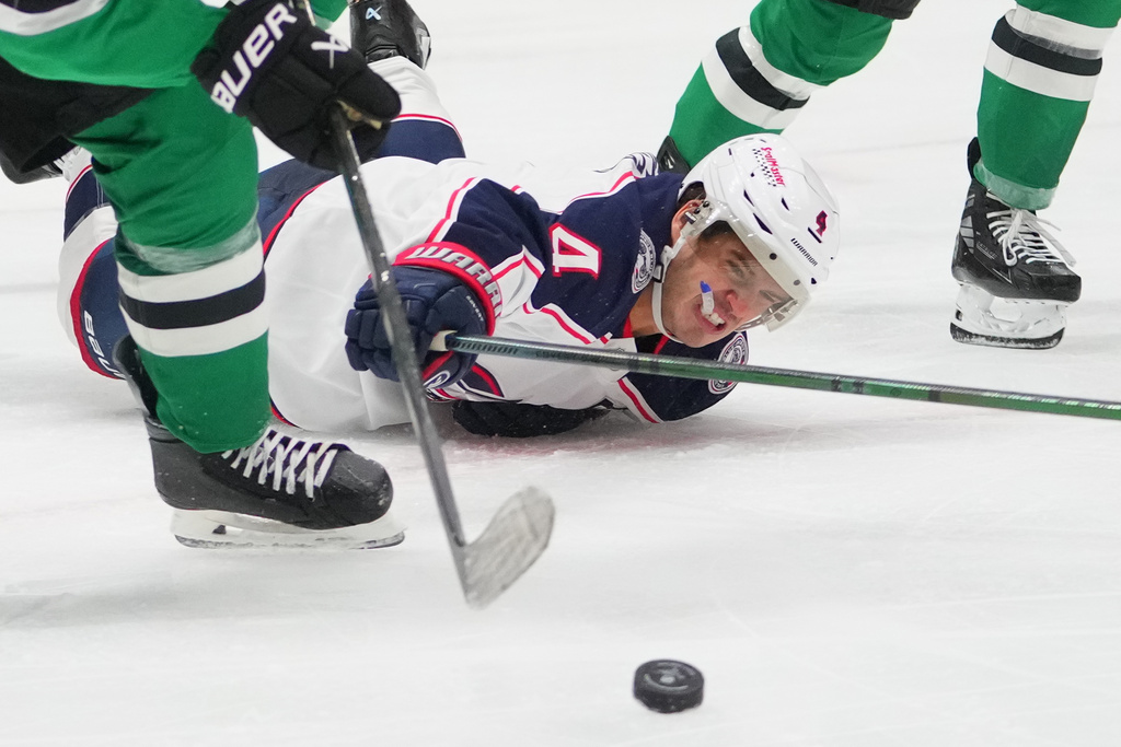 Columbus Blue Jackets center Cole Sillinger falls while attacking as Dallas Stars defenseman Ilya Lyubushkin, left, clears the puck out of his zone during the second period of an NHL hockey game Tuesday, Oct. 21, 2025, in Dallas. (AP Photo/Julio Cortez)