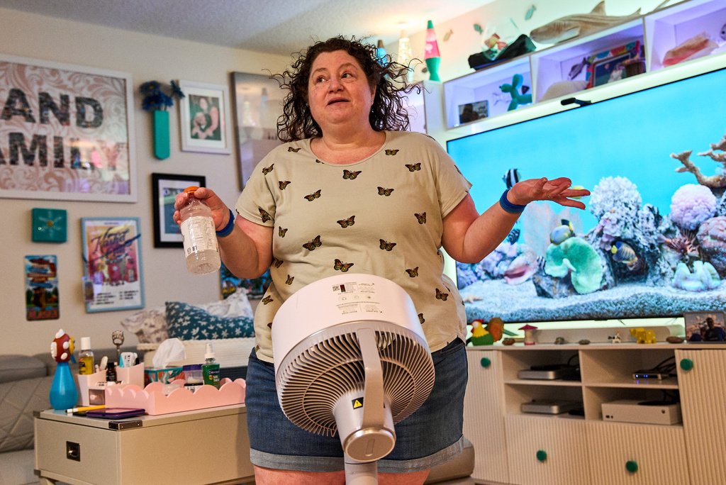 Tracy Rand uses a fan to help with her severe menopause symptoms, brought on after a surgery to remove her ovaries, at her home in Leesburg, Fla., Friday, Aug. 14, 2026. (AP Photo/Jacquelyn Martin)
