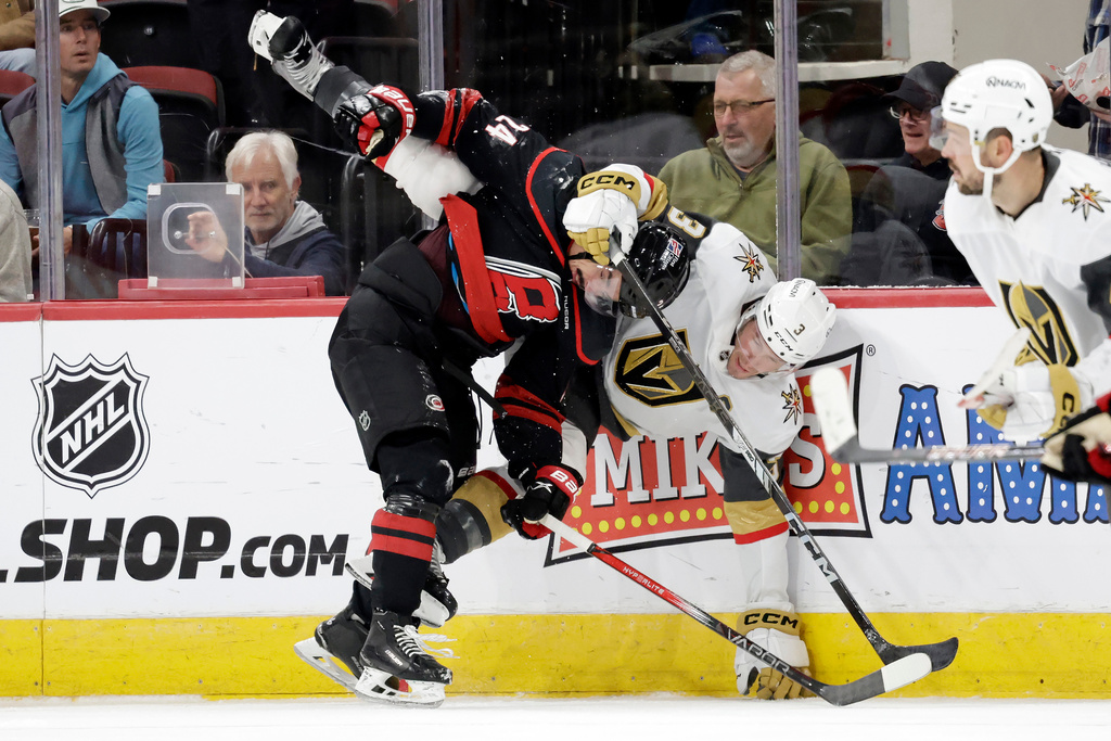 Carolina Hurricanes center Seth Jarvis (24) and Vegas Golden Knights defenseman Brayden McNabb (3) collide along the boards during the first period of an NHL hockey game Tuesday, Oct. 28, 2025, in Raleigh, N.C. (AP Photo/Chris Seward)