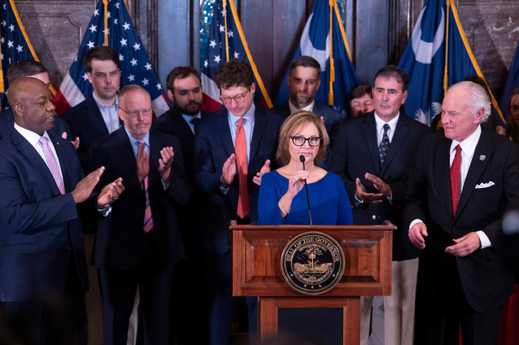 Newly appointed U.S. interim Senator, Darline Graham Nordone, with South Carolina Gov. Henry McMaster, right, and Sen. Tim Scott (R-SC), left, speaks to members of the press after being appointed of to fill the vacancy created by the passing of her brother, U.S. Senator Lindsey Graham, at the statehouse Monday, July 13, 2026, in Columbia, S.C. (AP Photo/Sean Rayford) CORRECTION: Corrects senator Scott's first name.