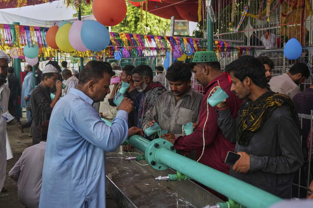 Devotees drink milk at a stall as they attend celebrations of the three-day annual festival or 'Urs' of mystic and scholar, Hazrat Ali Hajveri, popularly known as Data Ganj Bakhsh at his shrine, in Lahore, Pakistan, Wednesday, Aug. 13, 2025. (AP Photo/K.M. Chaudary)