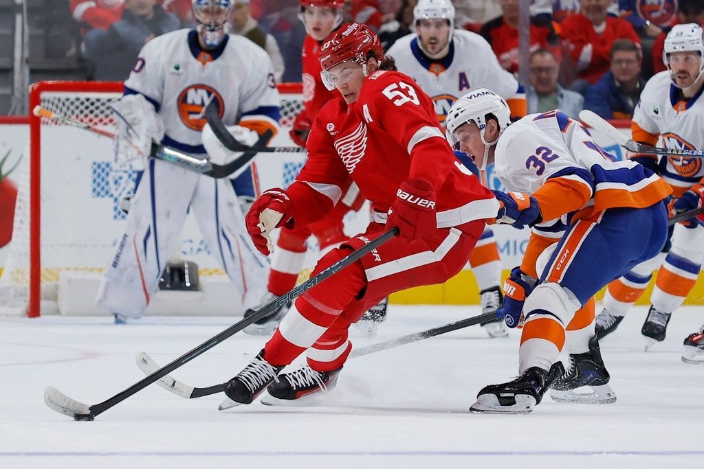 Detroit Red Wings defenseman Moritz Seider (53) keeps the puck away from New York Islanders center Kyle MacLean (32) during the first period of an NHL hockey game Tuesday, Dec. 16, 2025, in Detroit. (AP Photo/Duane Burleson)