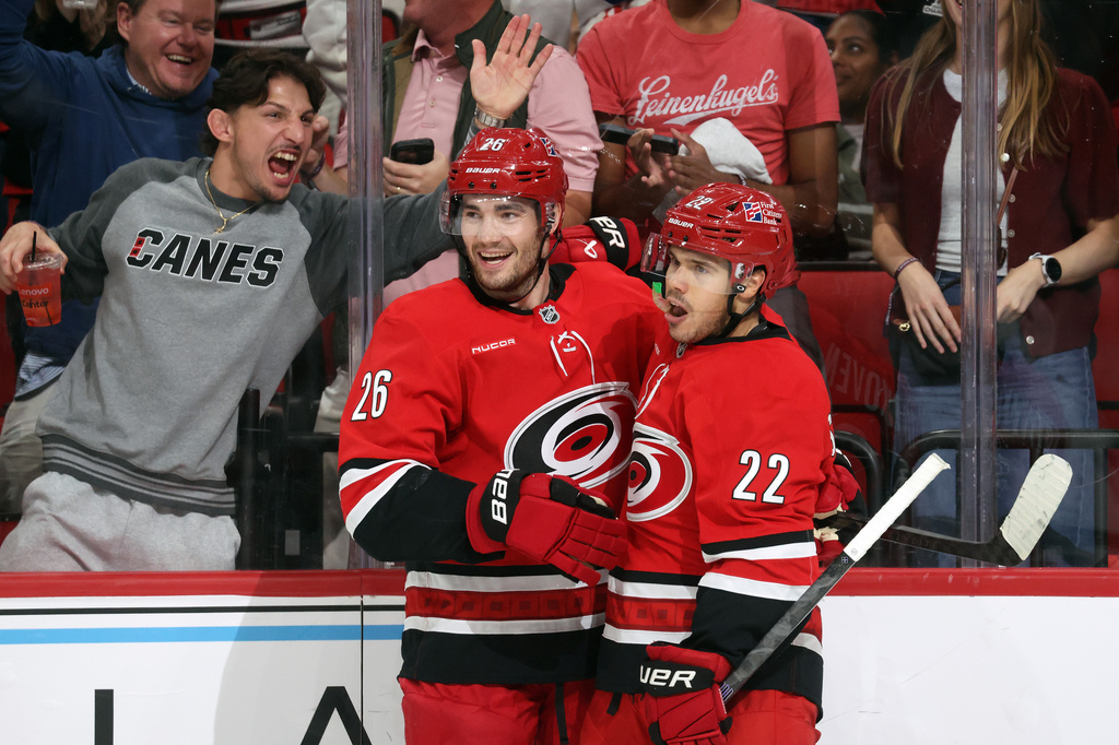 Carolina Hurricanes' Sean Walker (26) congratulates Logan Stankoven, right, on his goal during the second period of an NHL hockey game against the Vancouver Canucks in Raleigh, N.C., Thursday, Oct. 8, 2026. (AP Photo/Karl DeBlaker)