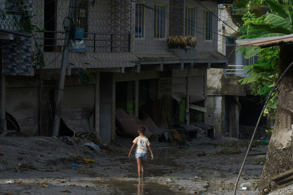 A child walks in mud in the aftermath of a flash floods in Devighat in the Nuwakot district in Nepal, Thursday, Aug 27, 2026. (AP Photo/Niranjan Shrestha)