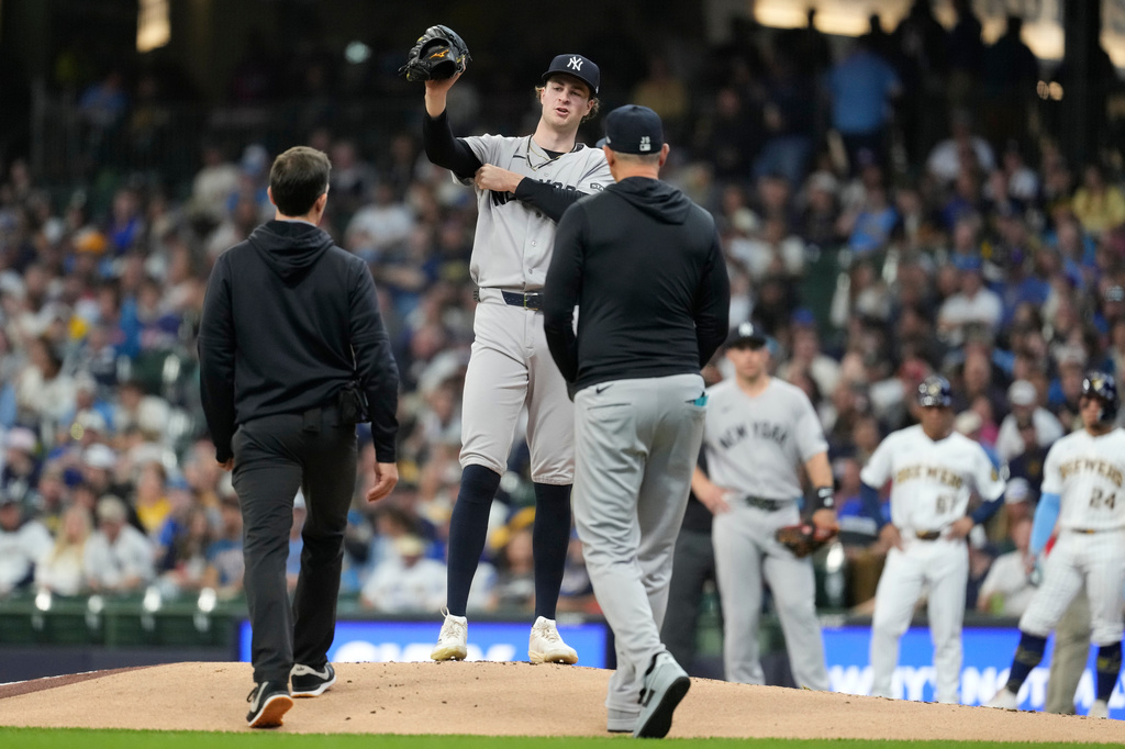 New York Yankees' Cam Schlittler talks with manager Aaron Boone and a trainer on the mound during the first inning of a baseball game against the Milwaukee Brewers, Saturday, May 9, 2026, in Milwaukee. (AP Photo/Aaron Gash)
