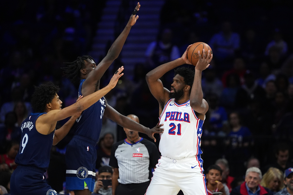 Philadelphia 76ers' Joel Embiid (21) tries to pass against Minnesota Timberwolves' Leonard Miller (33) and Joan Beringer (19) during the first half of a preseason NBA basketball game Friday, Oct. 17, 2025, in Philadelphia. (AP Photo/Matt Slocum)