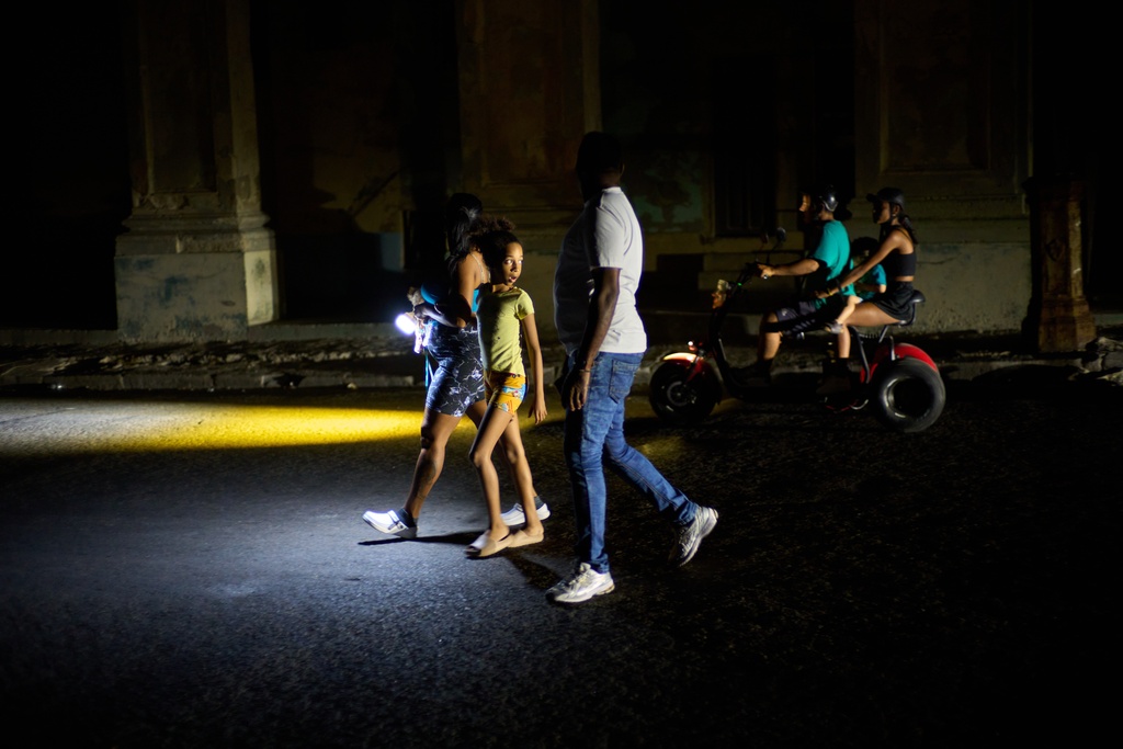 People walk on a street during a blackout in Havana, Monday, March 16, 2026. (AP Photo/Ramon Espinosa)