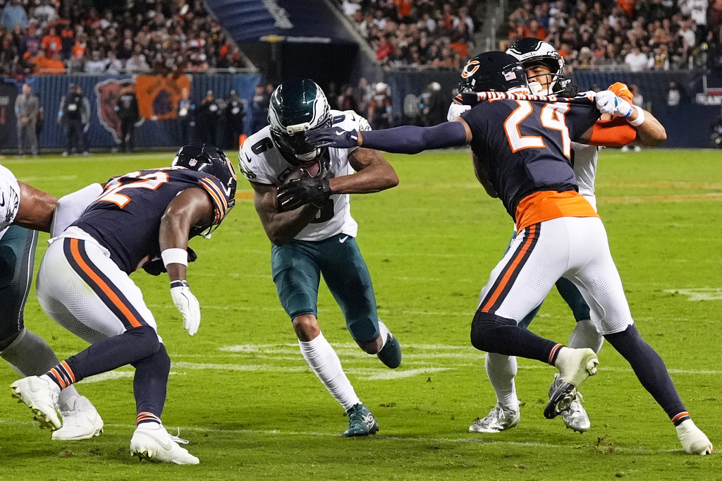Philadelphia Eagles wide receiver DeVonta Smith (6) runs the ball as Chicago Bears' Xavier Woods (32) an Malik Muhammad II (24) combine to make the stop during the first half of an NFL football game in Chicago, Monday, Sept. 28, 2026. (AP Photo/David Banks)