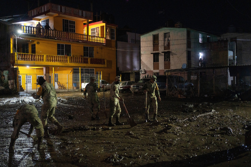 Soldiers clean a flooded street in Poza Rica, Veracruz state, Mexico, Tuesday, Oct. 14, 2025, after torrential rain. (AP Photo/Felix Marquez)