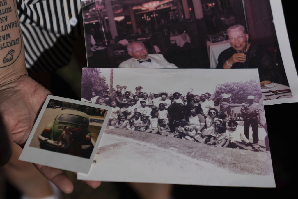 Brianna Wheeler holds family photos, including an image of her grandmother, top right, as she poses for photos at Peninsula Park, Monday, Sept. 22, 2025, in Portland, Ore. (AP Photo/Jenny Kane)