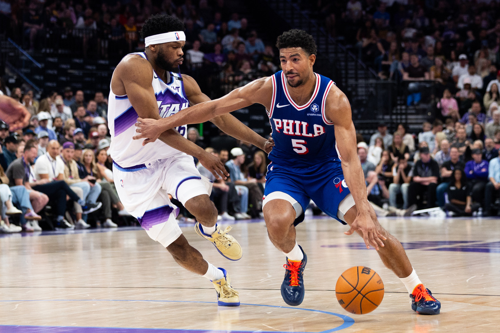 Philadelphia 76ers guard Quentin Grimes (5) dribbles around Utah Jazz guard Elijah Harkless, left, during the first half of an NBA basketball game, Saturday, March 21, 2026, in Salt Lake City. (AP Photo/Anna Fuder)