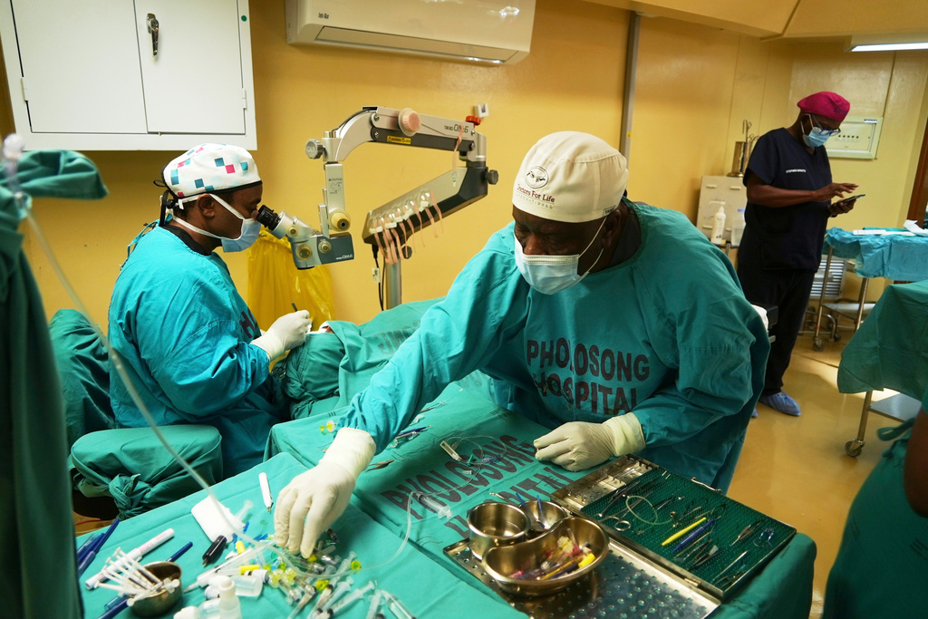 An ophthalmologist performs cataract surgery while an assistant hands him surgical instruments during a marathon event, in Tsakane, South Africa, Saturday, March 28, 2026. (AP Photo/Kayleen Morgan)