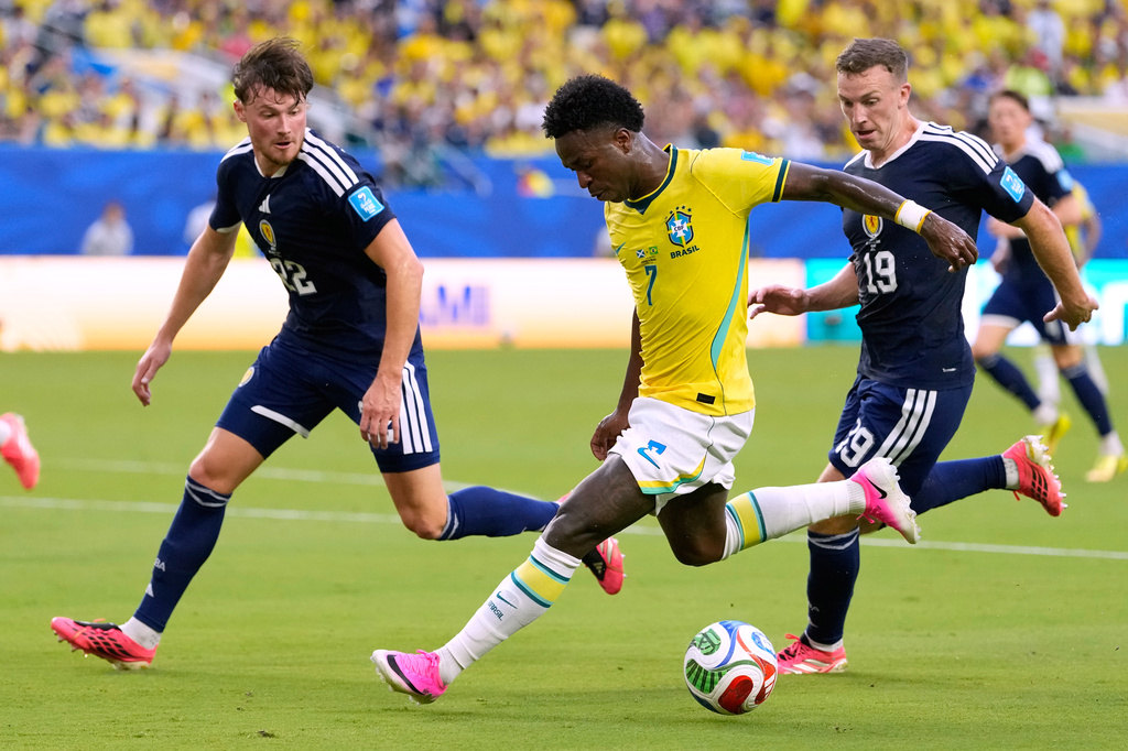 Brazil's Vinicius Junior (7) battles for the ball with with Scotland's Nathan Patterson (22) and Lewis Ferguson (19) during the World Cup Group C soccer match between Scotland and Brazil in Miami Gardens, Fla., Wednesday, June 24, 2026. (AP Photo/Rebecca Blackwell)