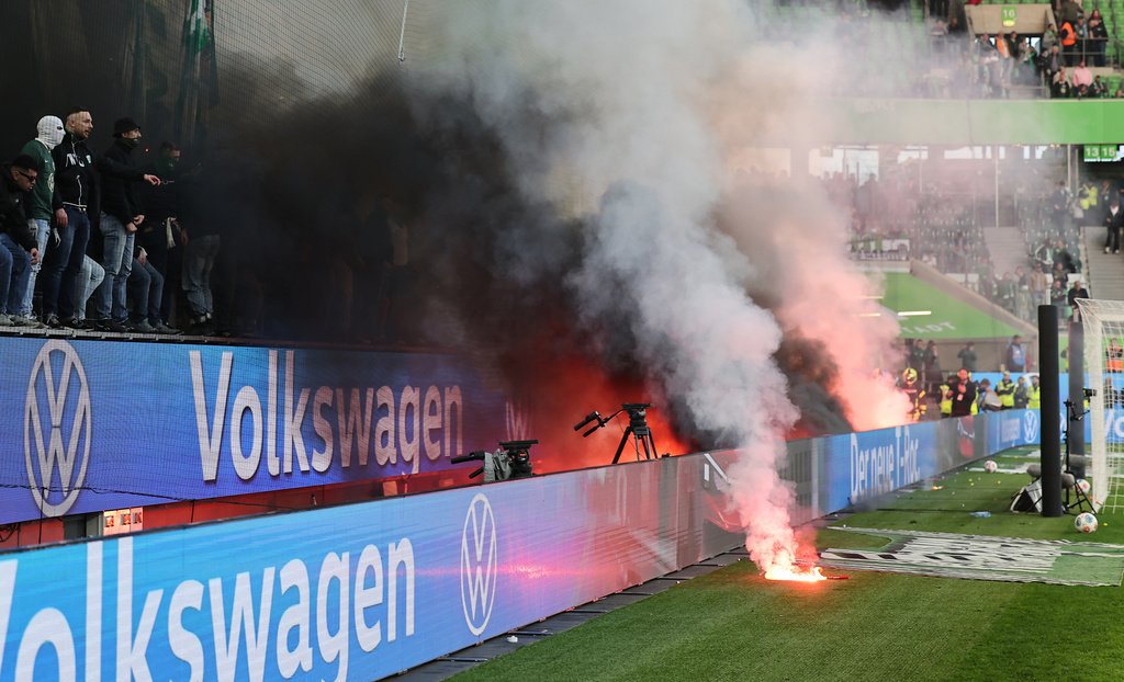 Wolfsburg fans throw flares onto the pitch following the German Bundesliga soccer match between Hamburger and Wolfsburg in Wolfsburg, Germany, Saturday, March 7, 2026. (Andreas Gora/dpa via AP)