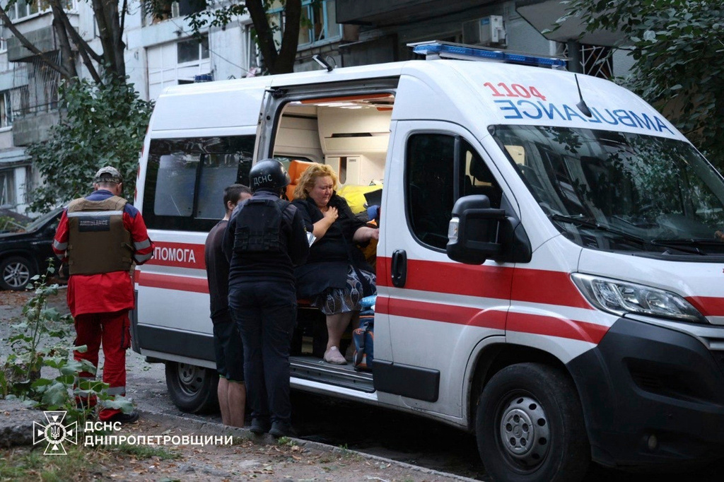 In this photo provided by the Ukrainian Emergency Services on Saturday, Sept. 20, 2025, an injured woman sits in ambulance near a residential house damaged by a Russian strike on Dnipro, Ukraine. (Ukrainian Emergency Service via AP)