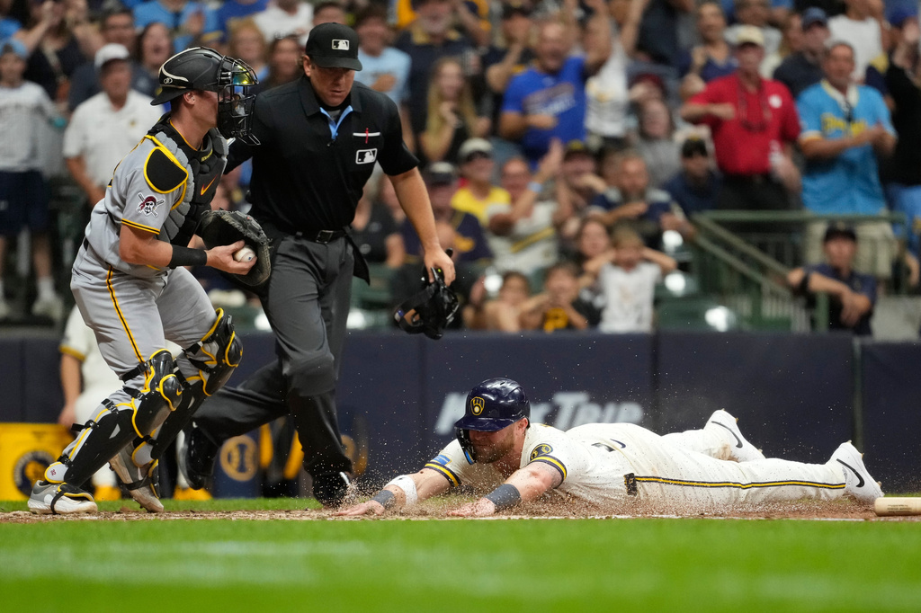 Milwaukee Brewers' Jake Bauers, right, slides into home plate to score a run past Pittsburgh Pirates' Henry Davis during the sixth inning of a baseball game Monday, Aug. 3, 2026, in Milwaukee. (AP Photo/Aaron Gash)