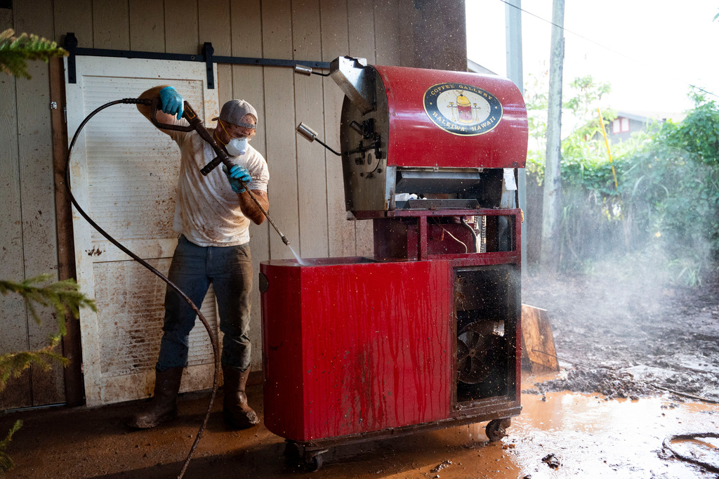 Nate Knaggs pressure washes a coffee roaster at his home damaged by flooding, Tuesday, March 24, 2026, in Haleiwa, Hawaii. (AP Photo/Mengshin Lin)
