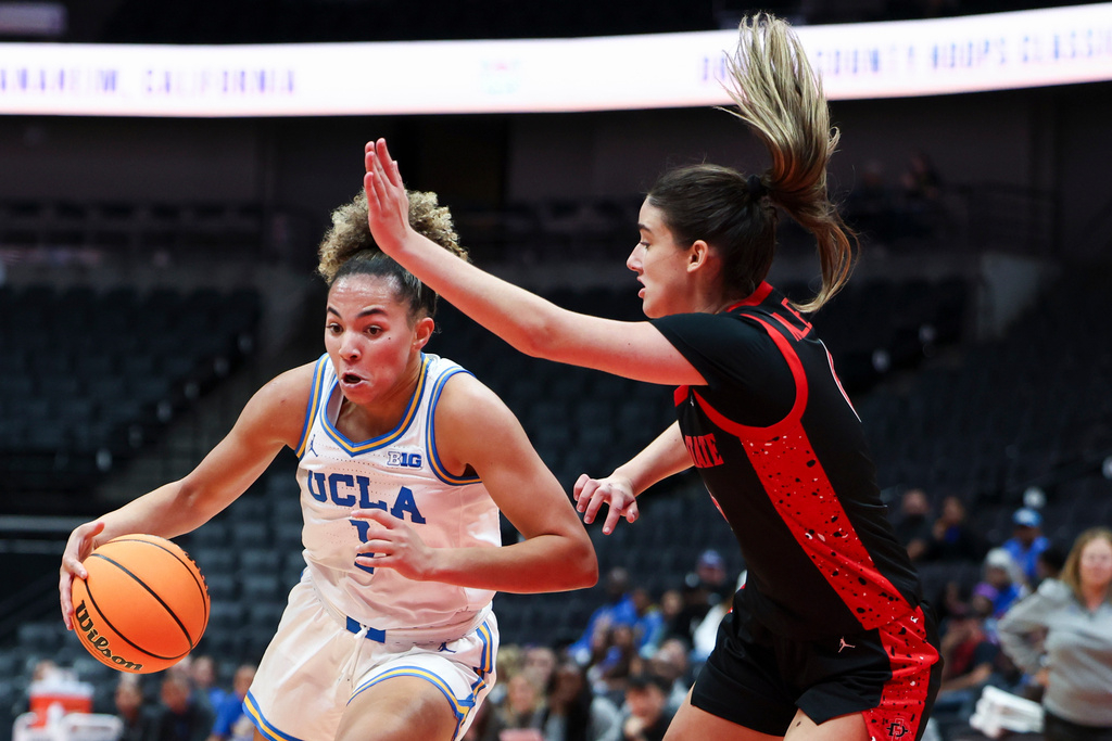 UCLA guard Kiki Rice, left, drives against San Diego State forward Sofia Kelemeni, right, during the first half of an NCAA college basketball game Monday, Nov. 3, 2025, in Anaheim, Calif. (AP Photo/Jessie Alcheh)